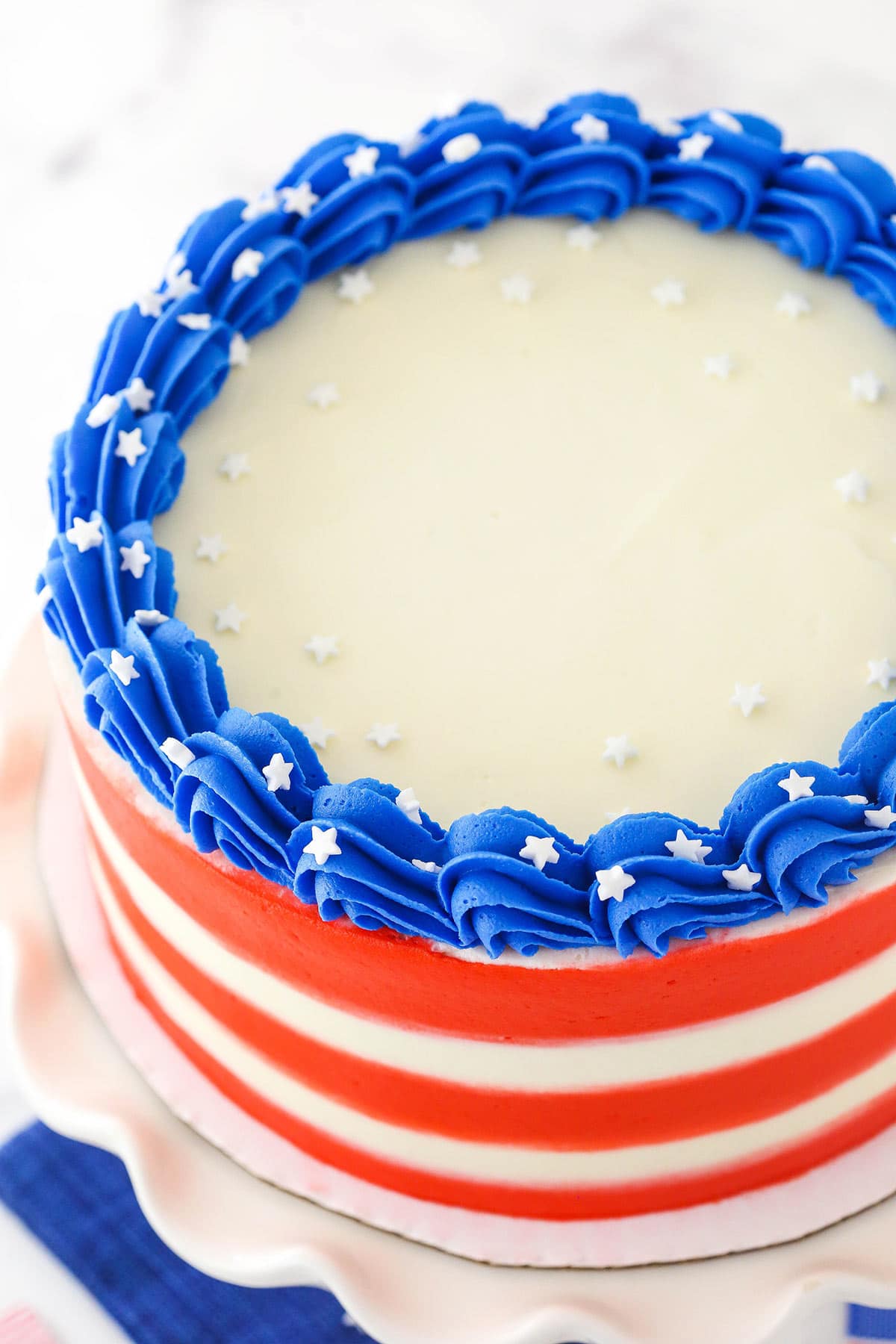 A July 4th marble cake on a white cake stand with white sprinkles garnishing the cake