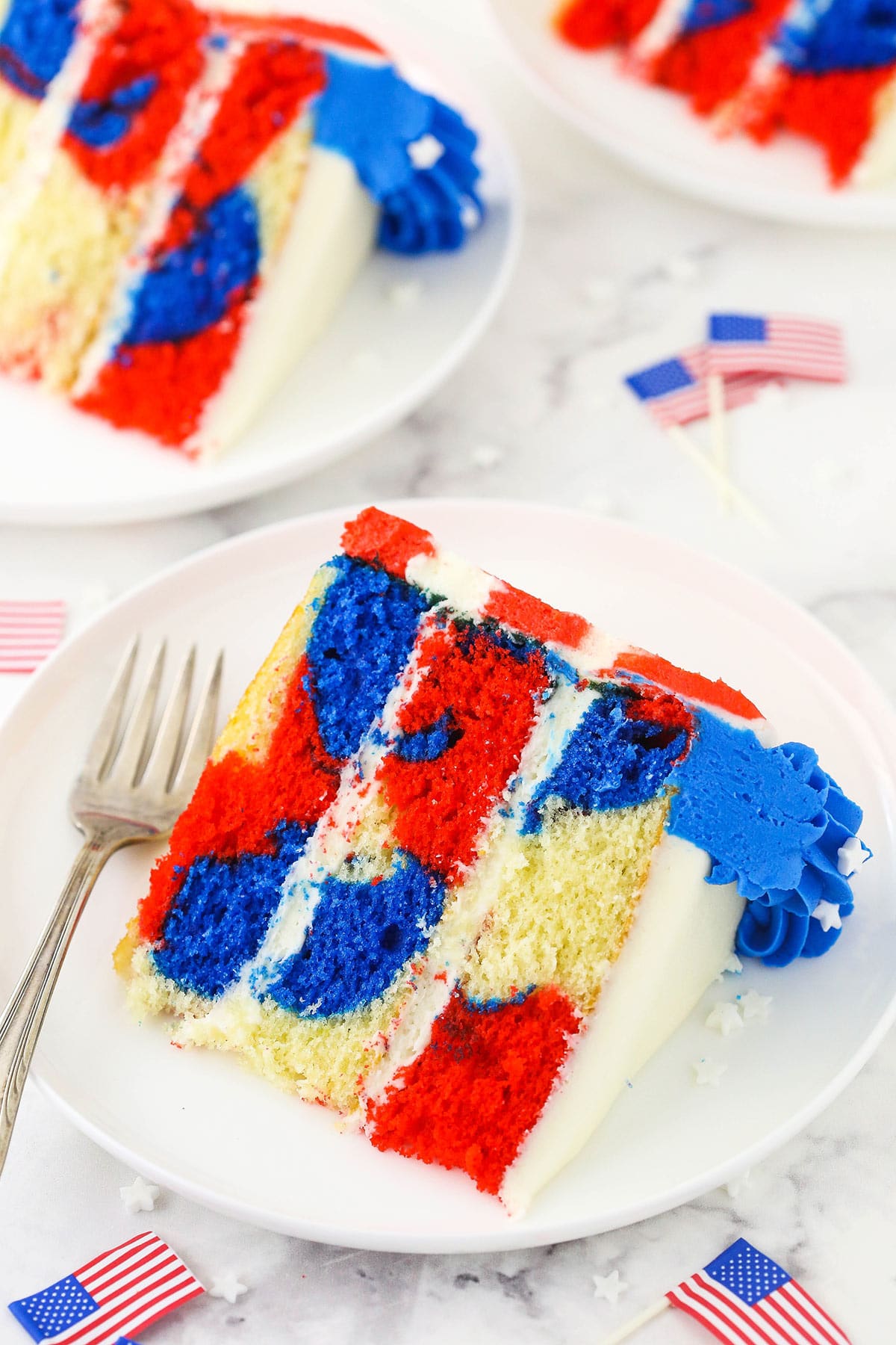 Three slices of red, white and blue marble cake on a granite kitchen countertop