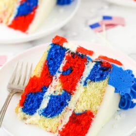 A piece of July 4th cake on a plate with two more slices behind it