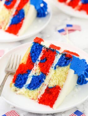 A piece of July 4th cake on a plate with two more slices behind it