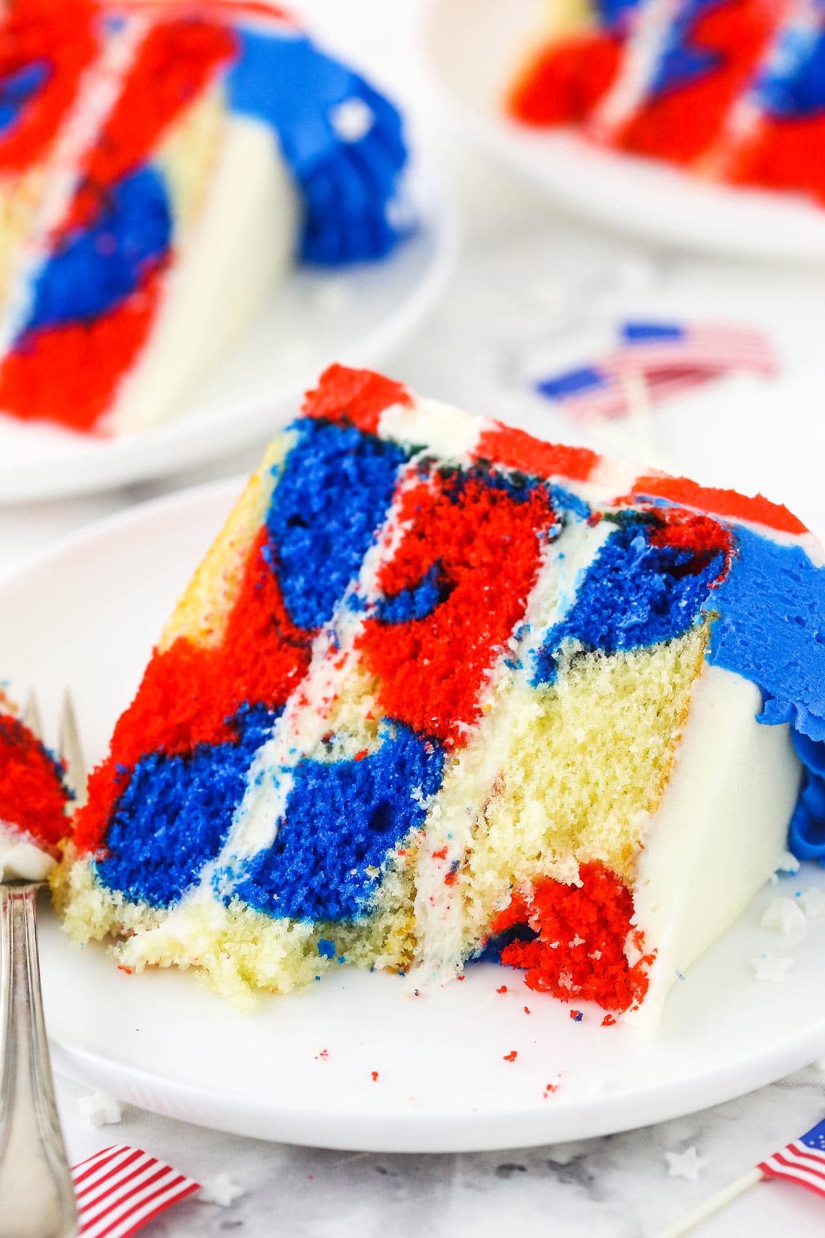 A slice of red, white and blue cake on a plate with a few bites taken out