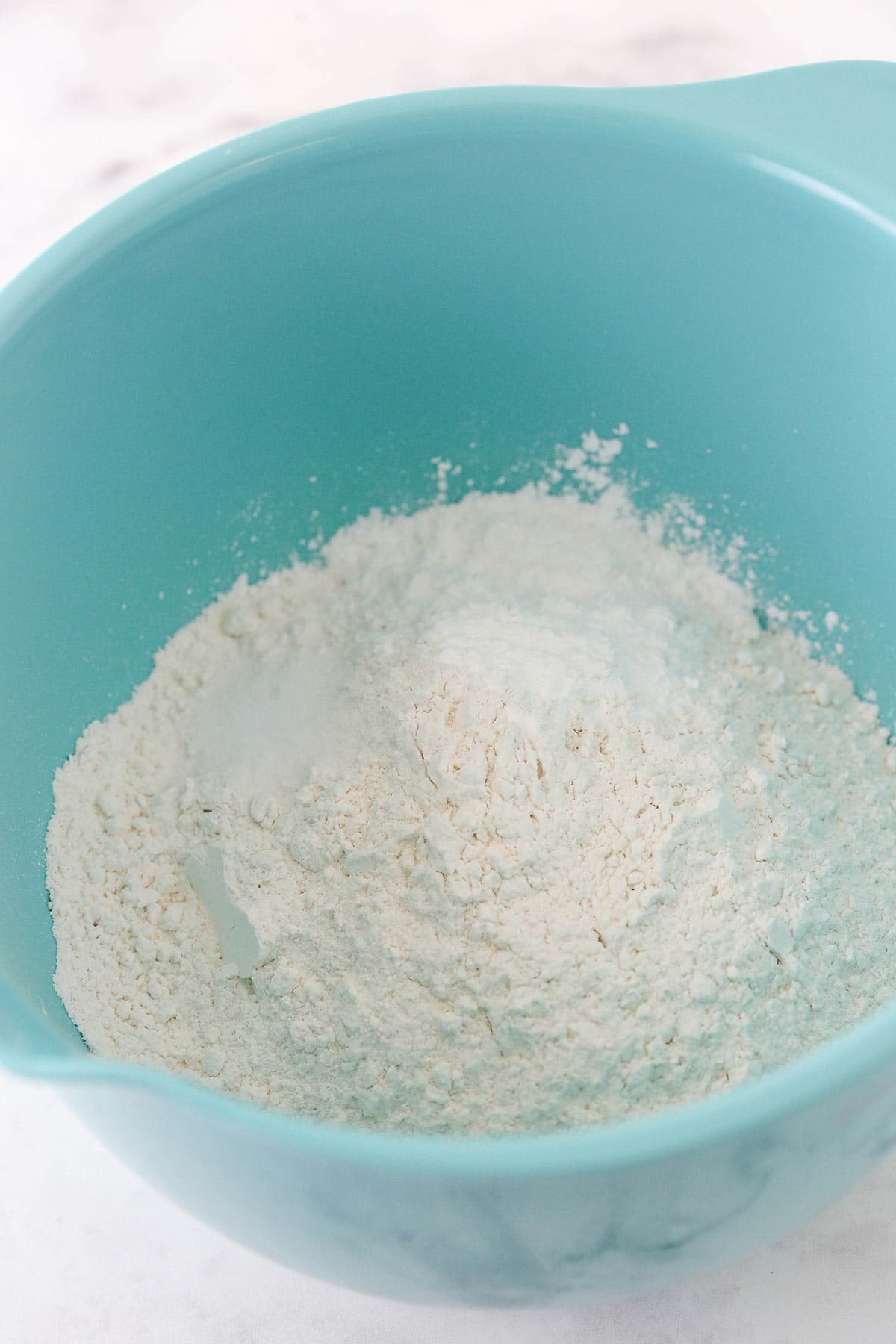 The combined dry ingredients inside of a light blue mixing bowl