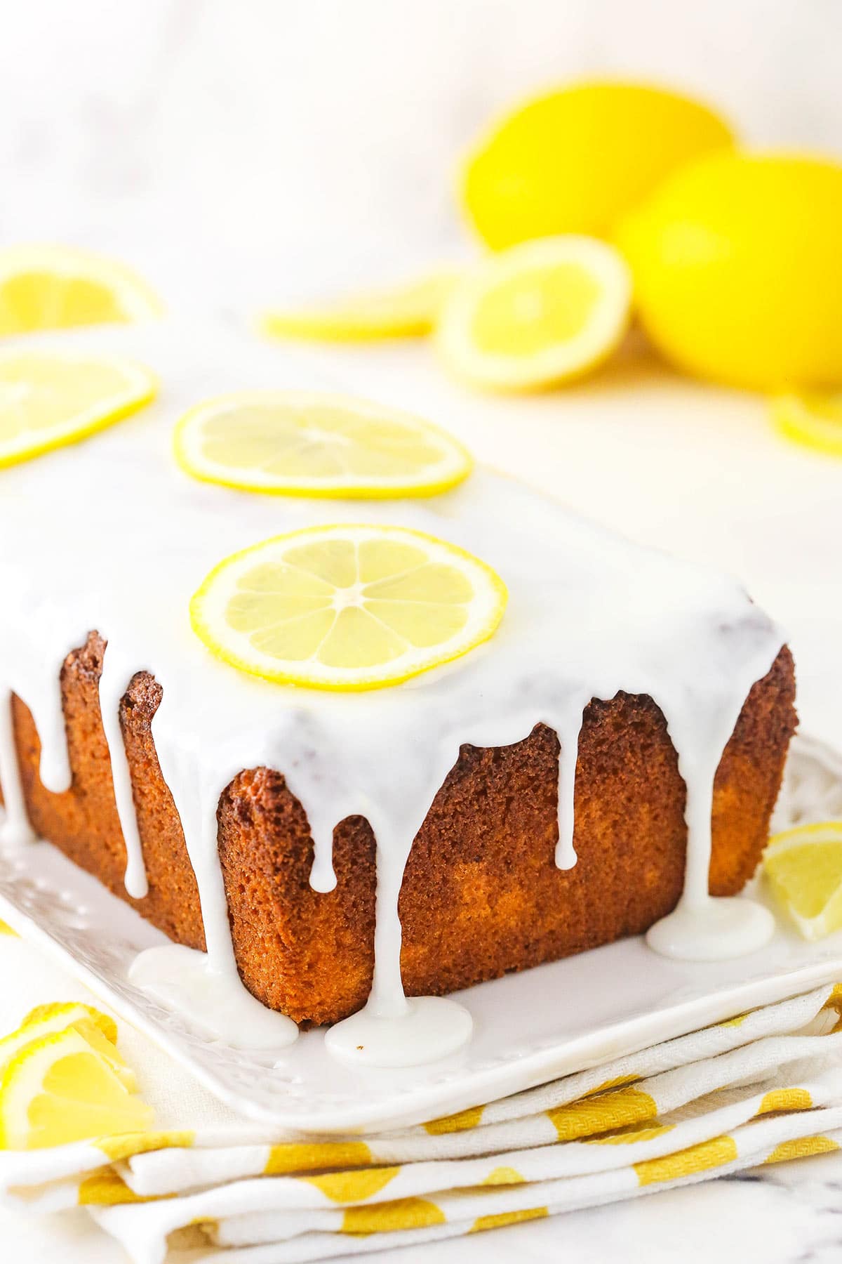 A cooled lemon loaf cake with icing-glaze and thin lemon slices on top