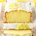 About half of a lemon loaf on a rectangular platter with two slices cut off of it