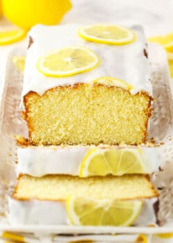 About half of a lemon loaf on a rectangular platter with two slices cut off of it