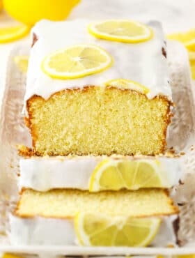 About half of a lemon loaf on a rectangular platter with two slices cut off of it