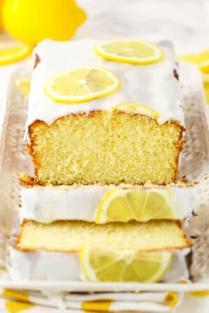 About half of a lemon loaf on a rectangular platter with two slices cut off of it