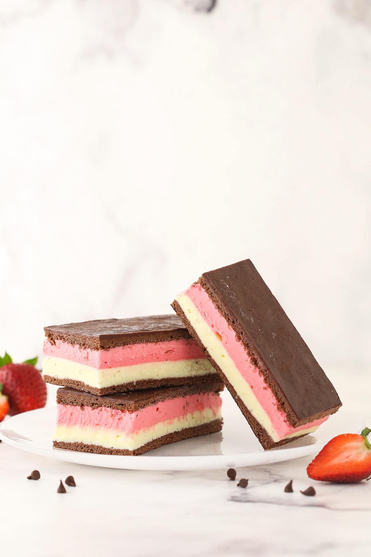 Two homemade ice cream sandwiches stacked on a plate with a third one propped up against them