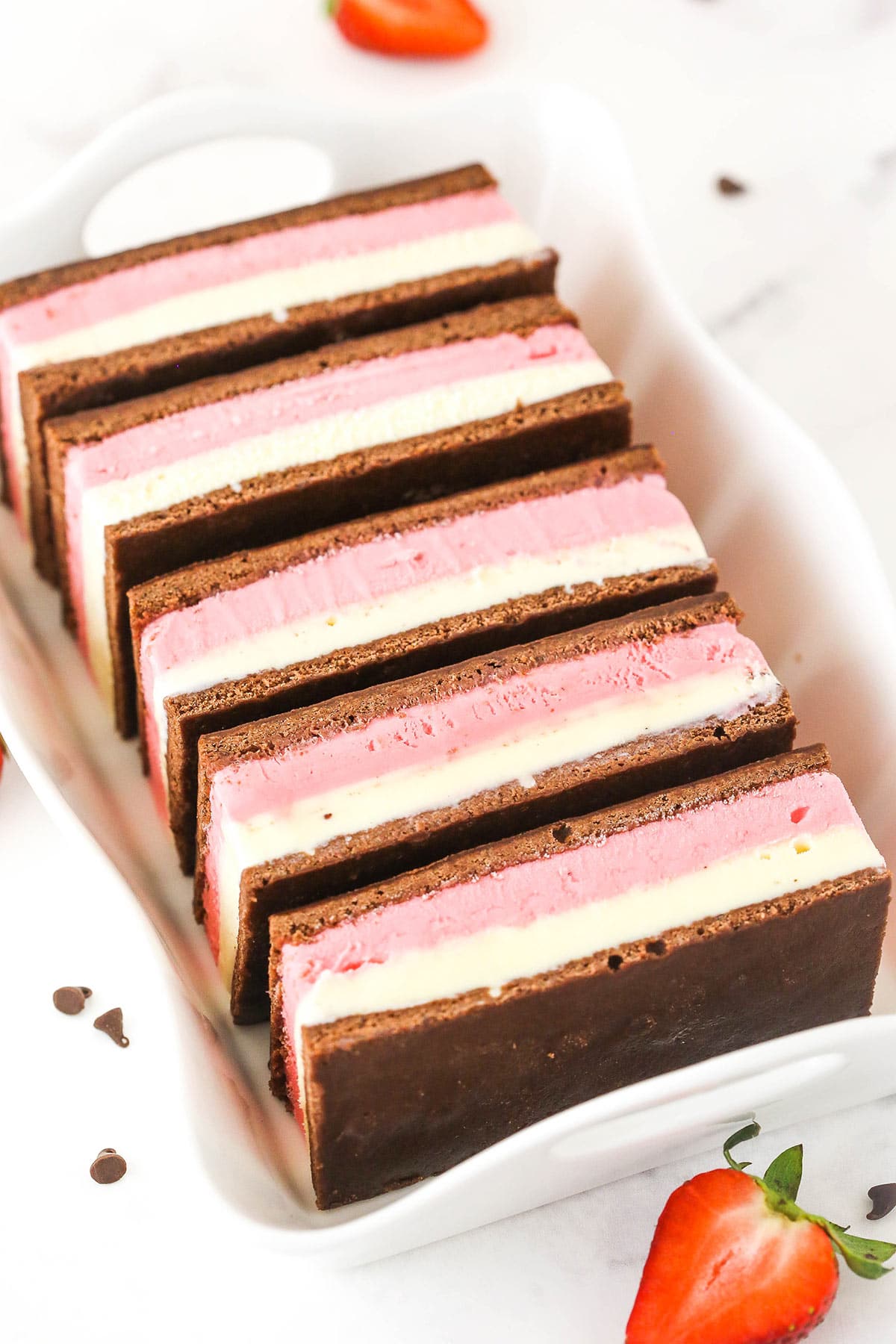 Five Neapolitan ice cream sandwiches lined up in a baking dish with handles