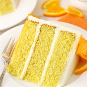 A close-up shot of a piece of cake on a plate on top of a cloth napkin