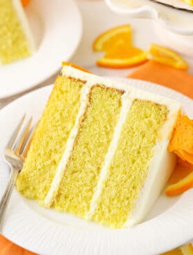 A close-up shot of a piece of cake on a plate on top of a cloth napkin