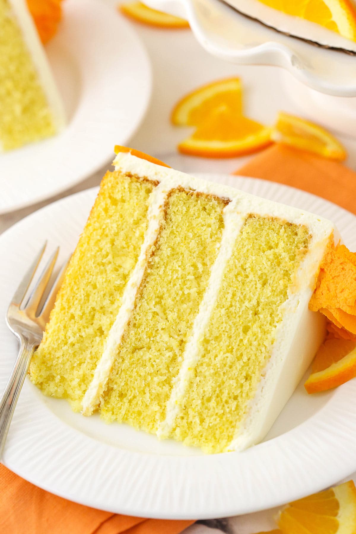 A close-up shot of a piece of cake on a plate on top of a cloth napkin