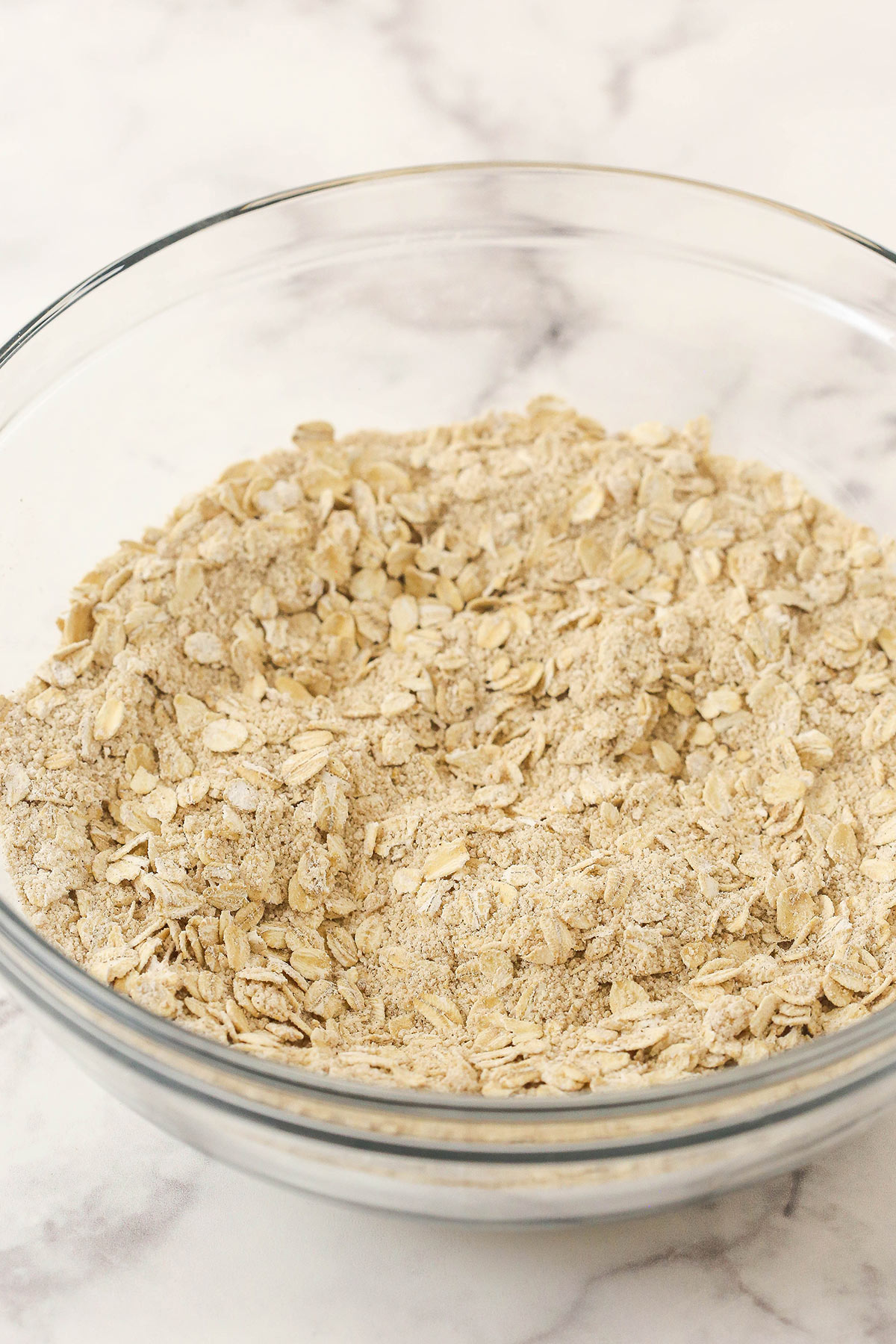 The flour, oats, brown sugar, cinnamon and salt combined in a glass bowl.