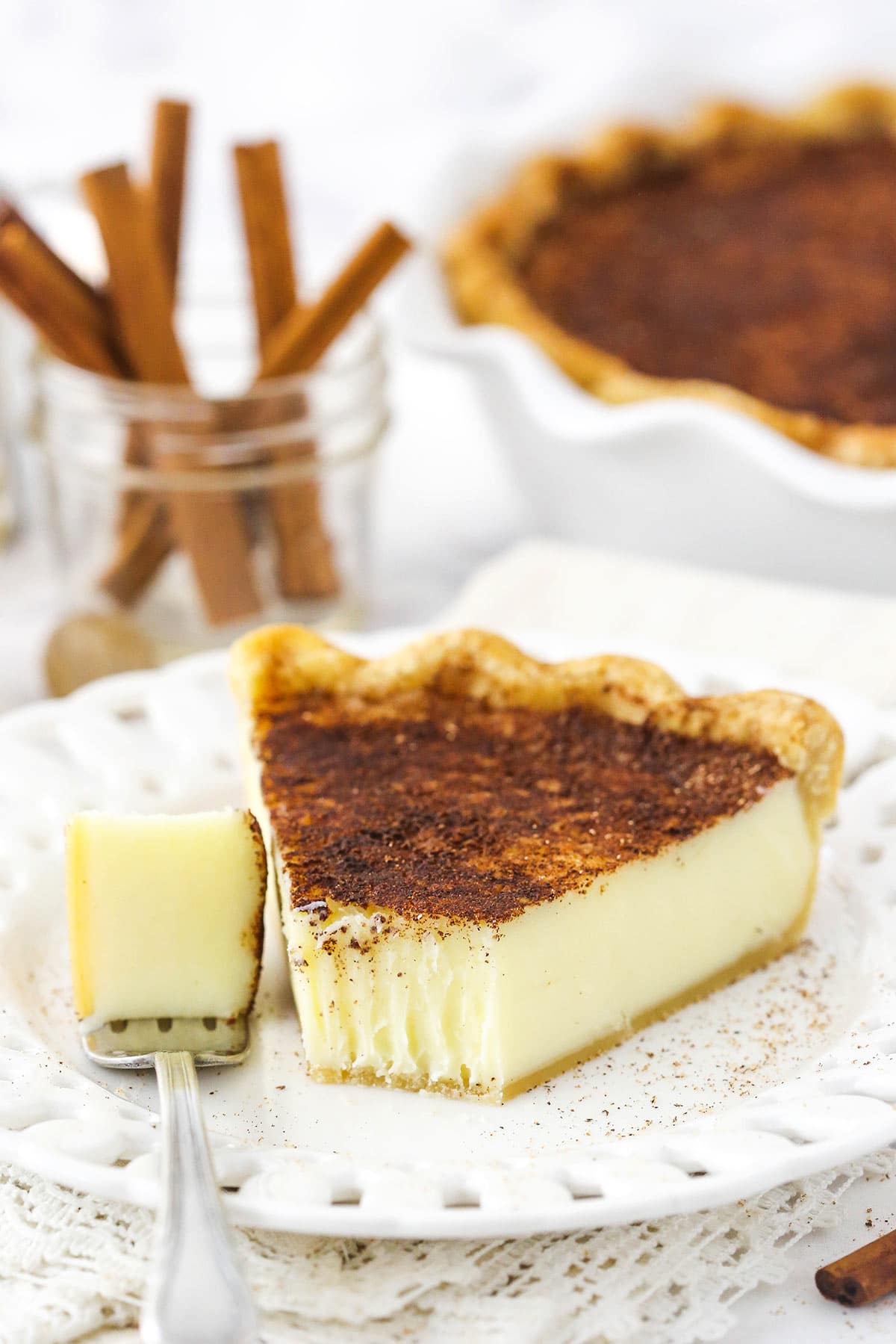 A slice of pie on a plate with one bite on a metal fork next to it