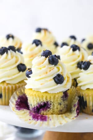 A blueberry coconut cupcake on a cake stand with the cupcake wrapper removed