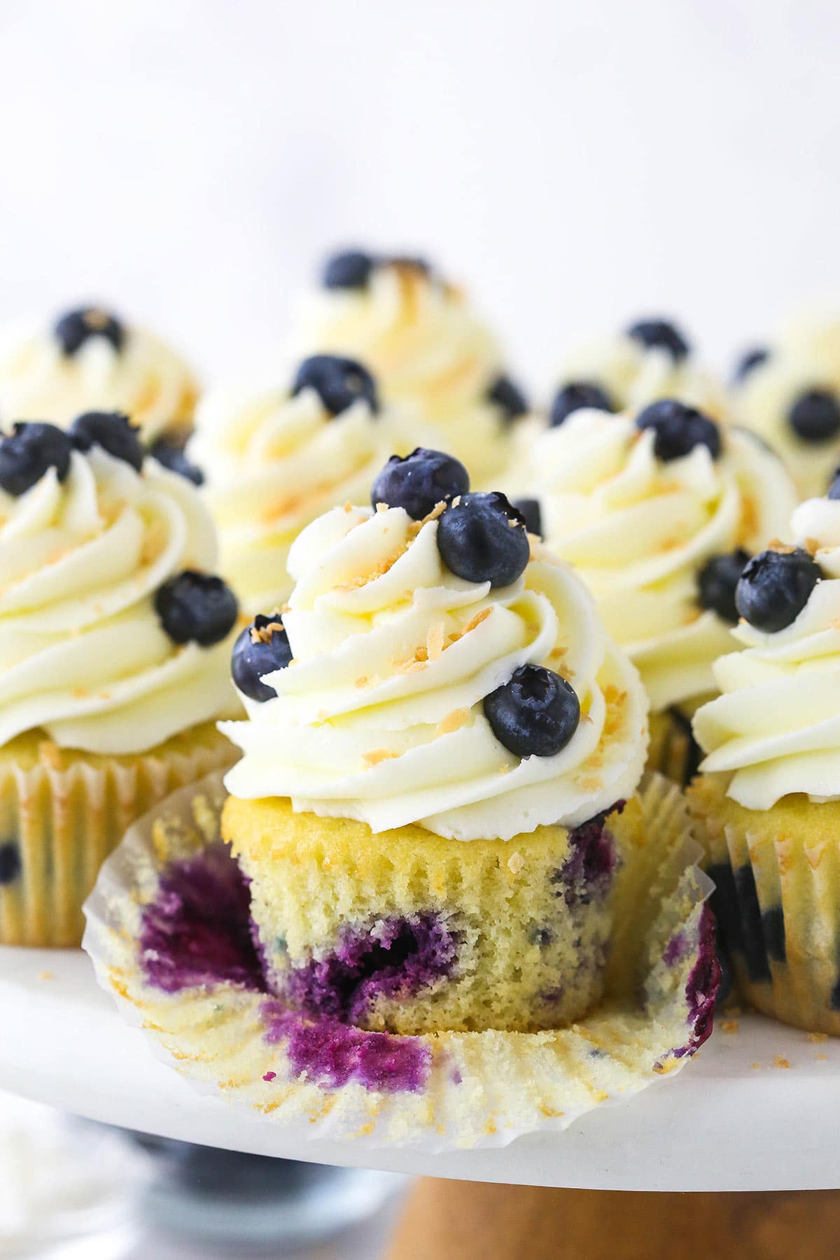 A blueberry coconut cupcake on a cake stand with the cupcake wrapper removed