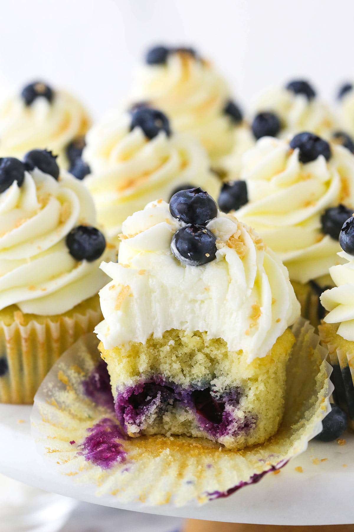 An unwrapped blueberry coconut cupcake with a big bite taken out of it