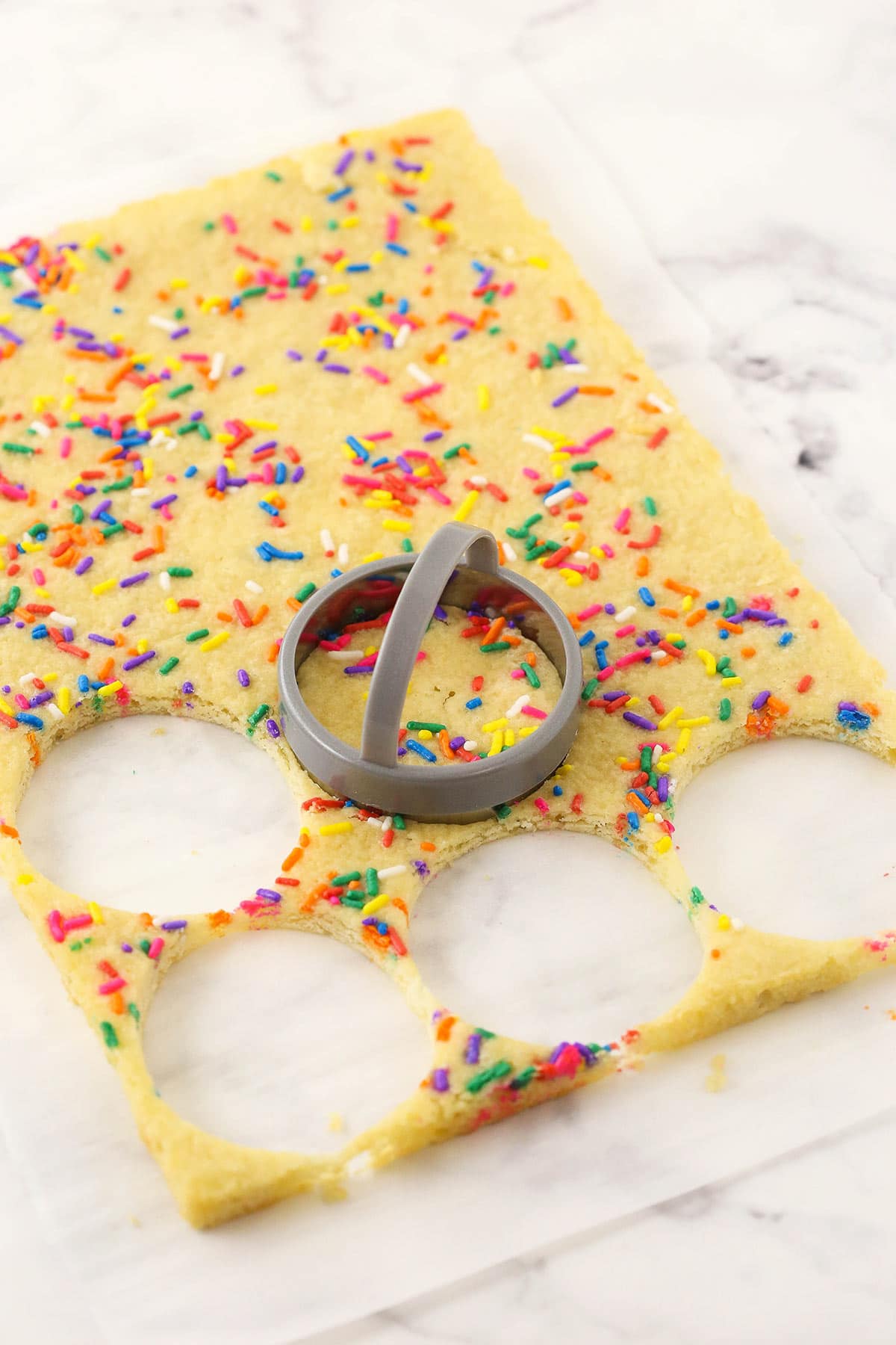Small circles being cut out of a thin layer of homemade confetti cake
