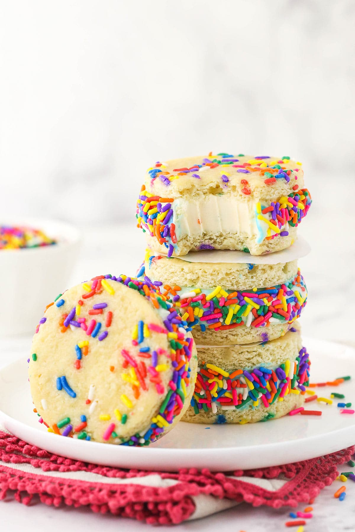 Four cake batter ice cream sandwiches on a plate with one missing a bite