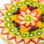 A fully decorated fruit pizza placed on a marble kitchen countertop