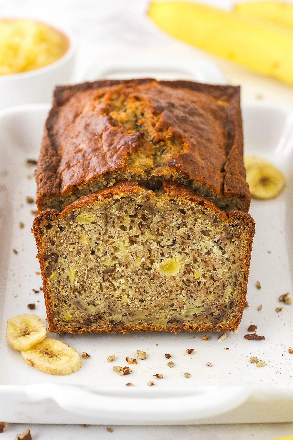 A slice of pineapple banana bread leaning up against half a loaf of the same bread