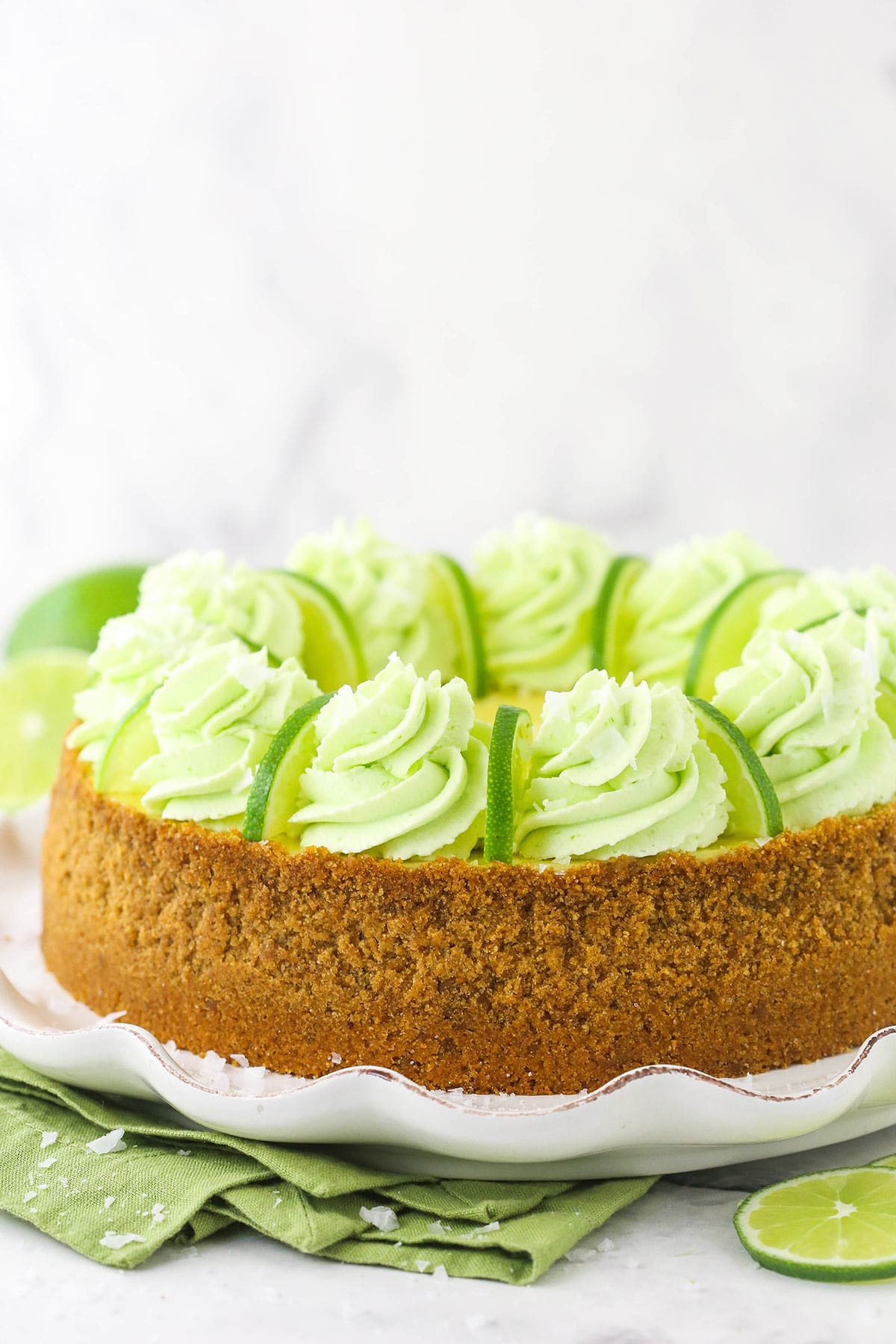 The side view of a tequila lime cake topped with tequila whipped cream and thin lime slices