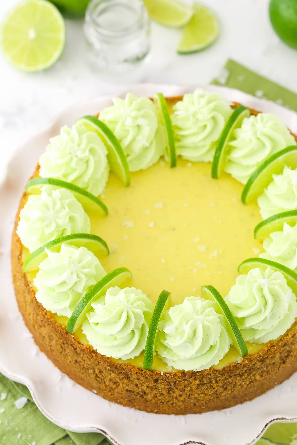 A whole margarita cheesecake on a white cake stand with a wavy rim