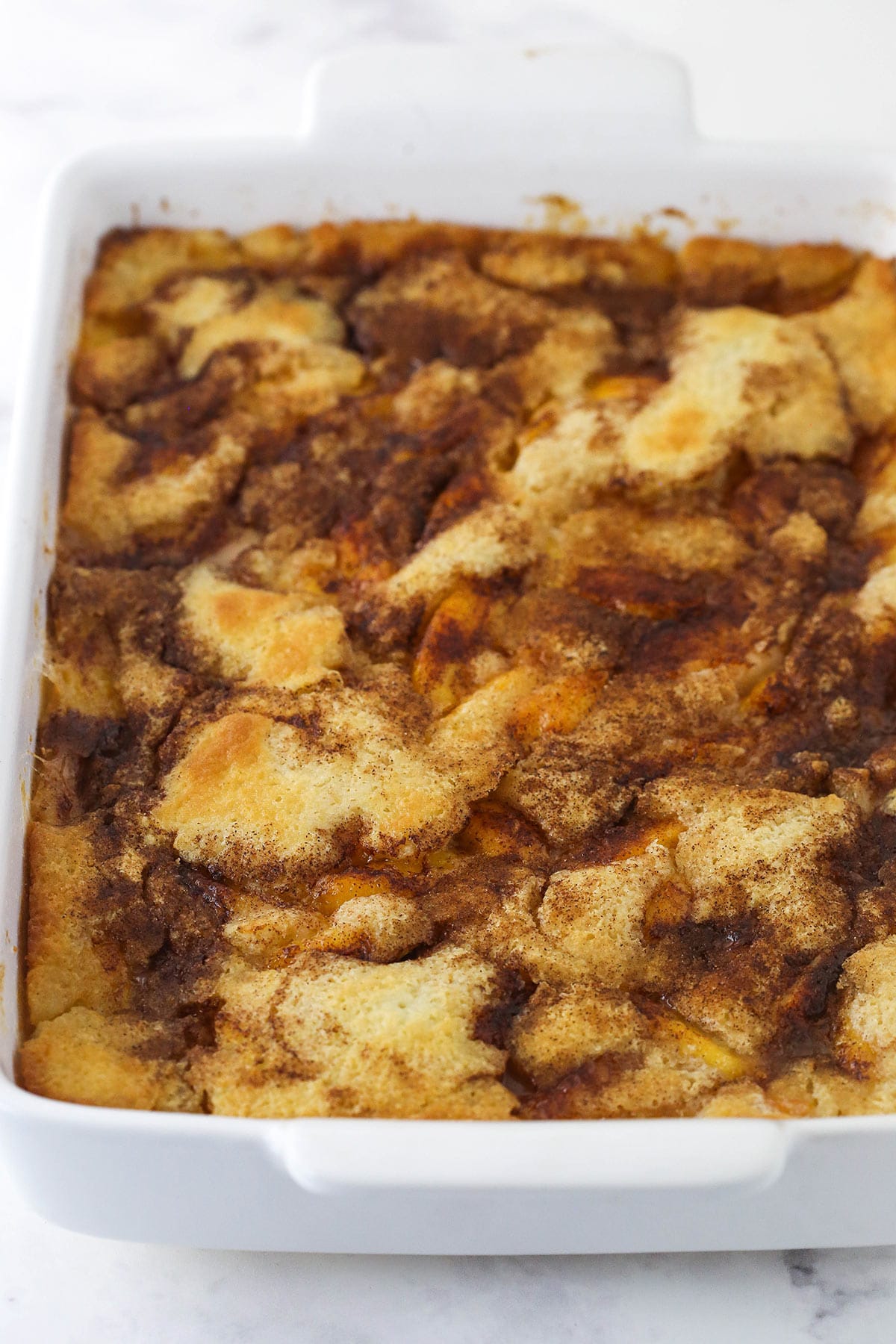 baked peach cobbler in white casserole dish