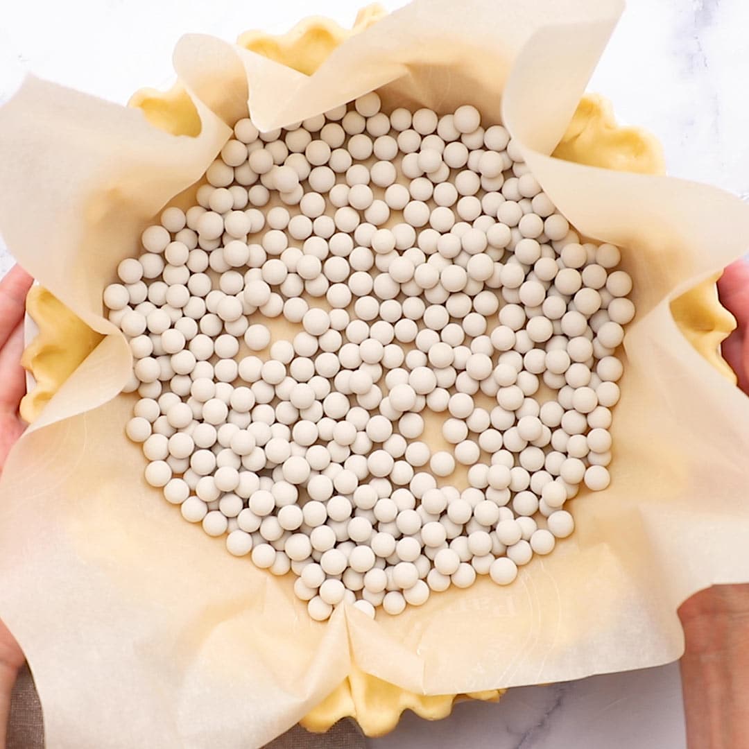 pie crust with parchment and pie weights in it to prepare for blind baking