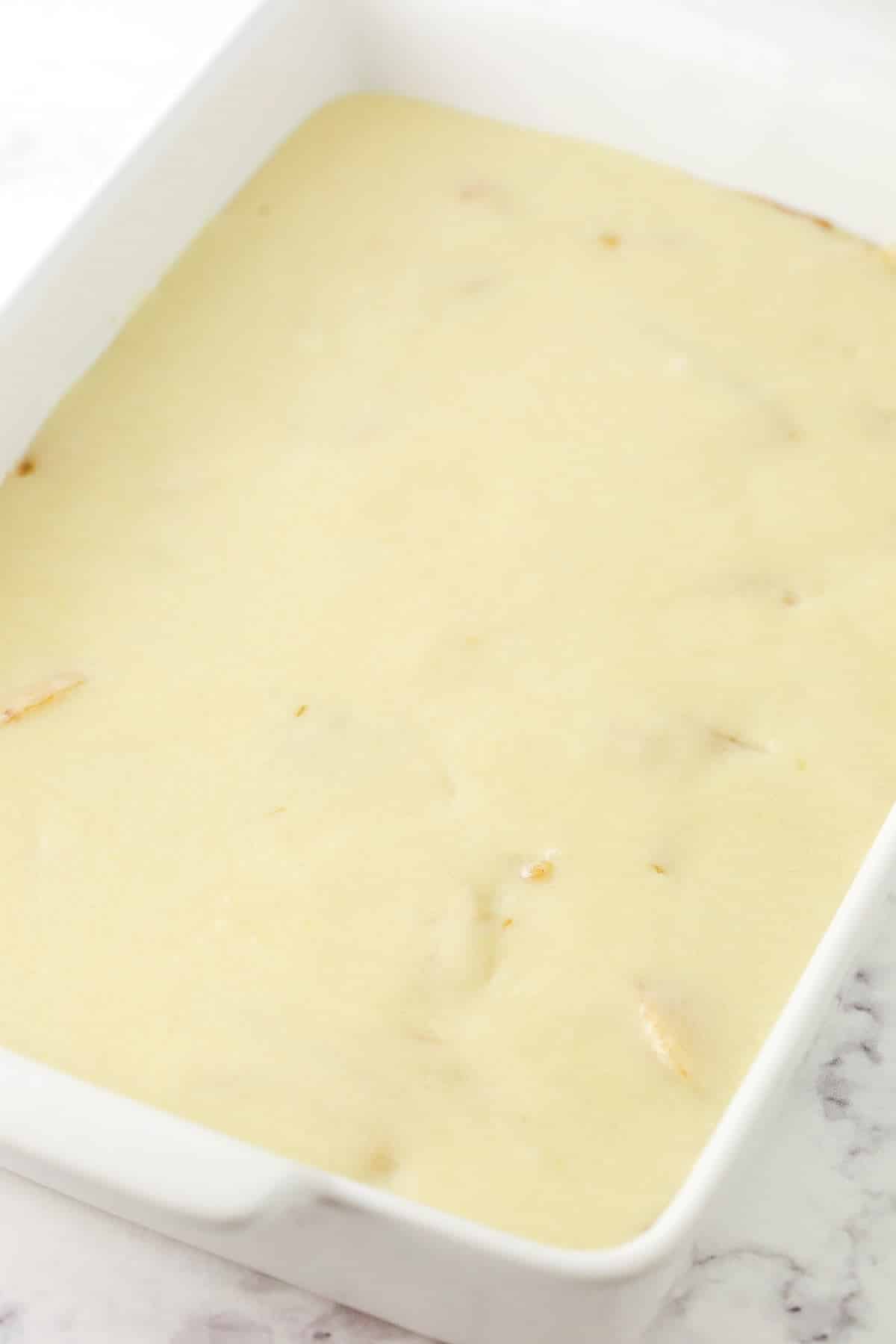 The batter poured evenly on top of the filling inside of a rectangular baking dish.