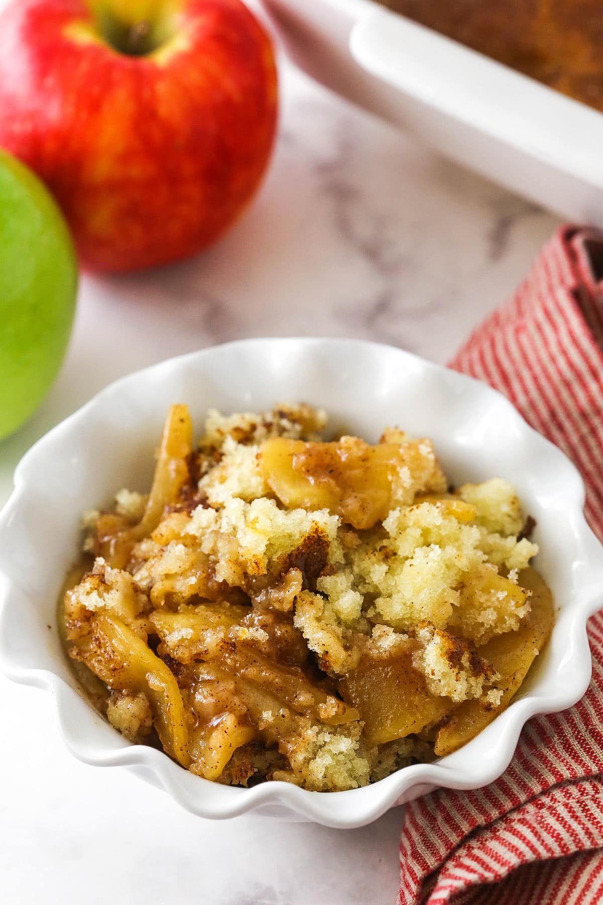 A serving of homemade apple cobbler in a bowl on a marble countertop.