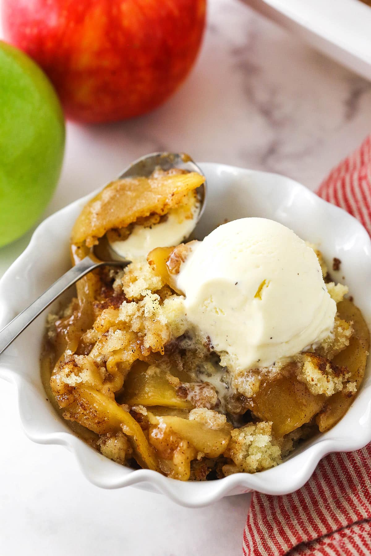 Filled with a sweet, melt-in-your-mouth cinnamon apple filling, this light and fluffy apple cobbler is truly the stuff dreams are made of! A bowl of apple cobbler topped with a scoop of vanilla bean ice cream.