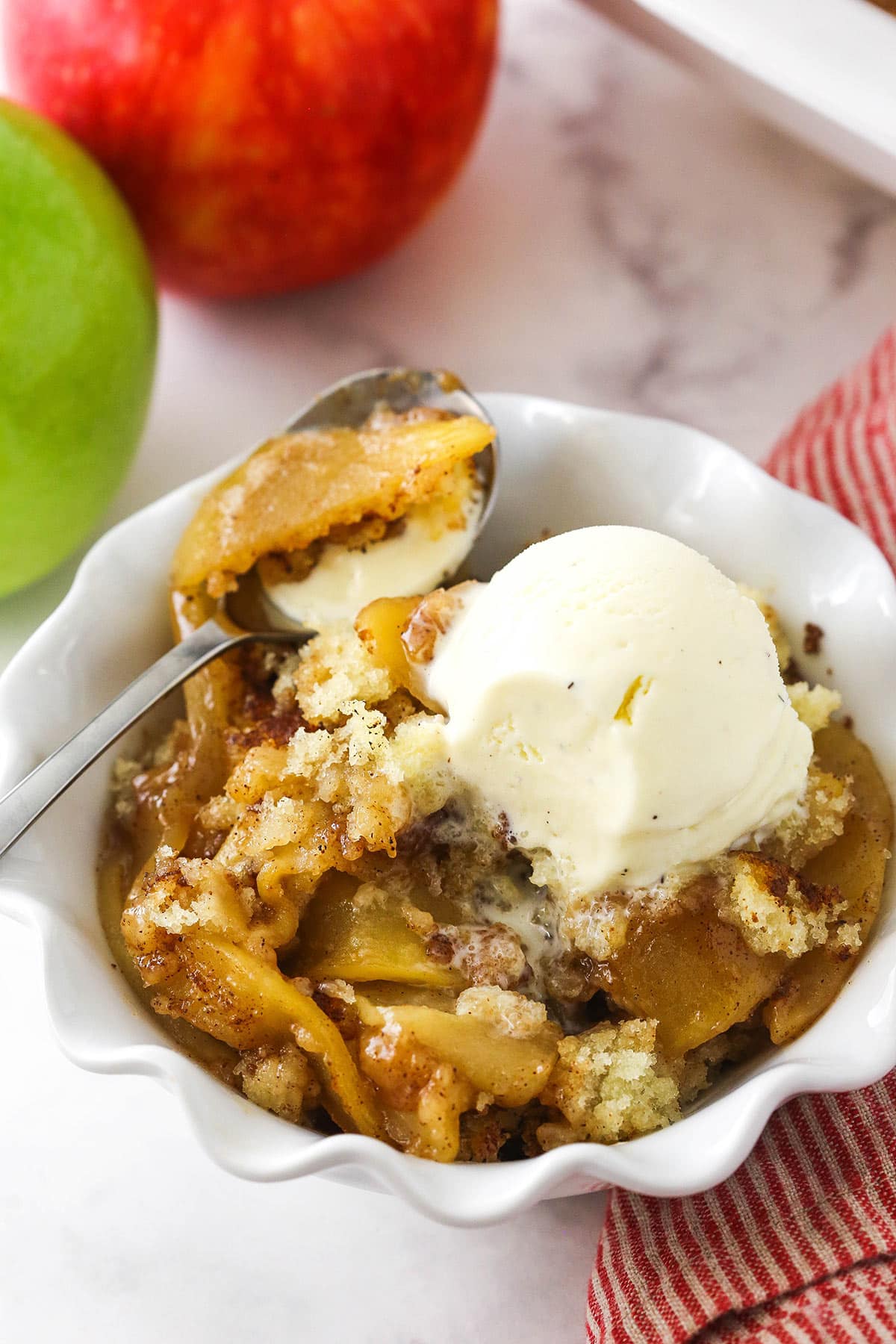 A bowl of apple cobbler topped with a scoop of vanilla bean ice cream.