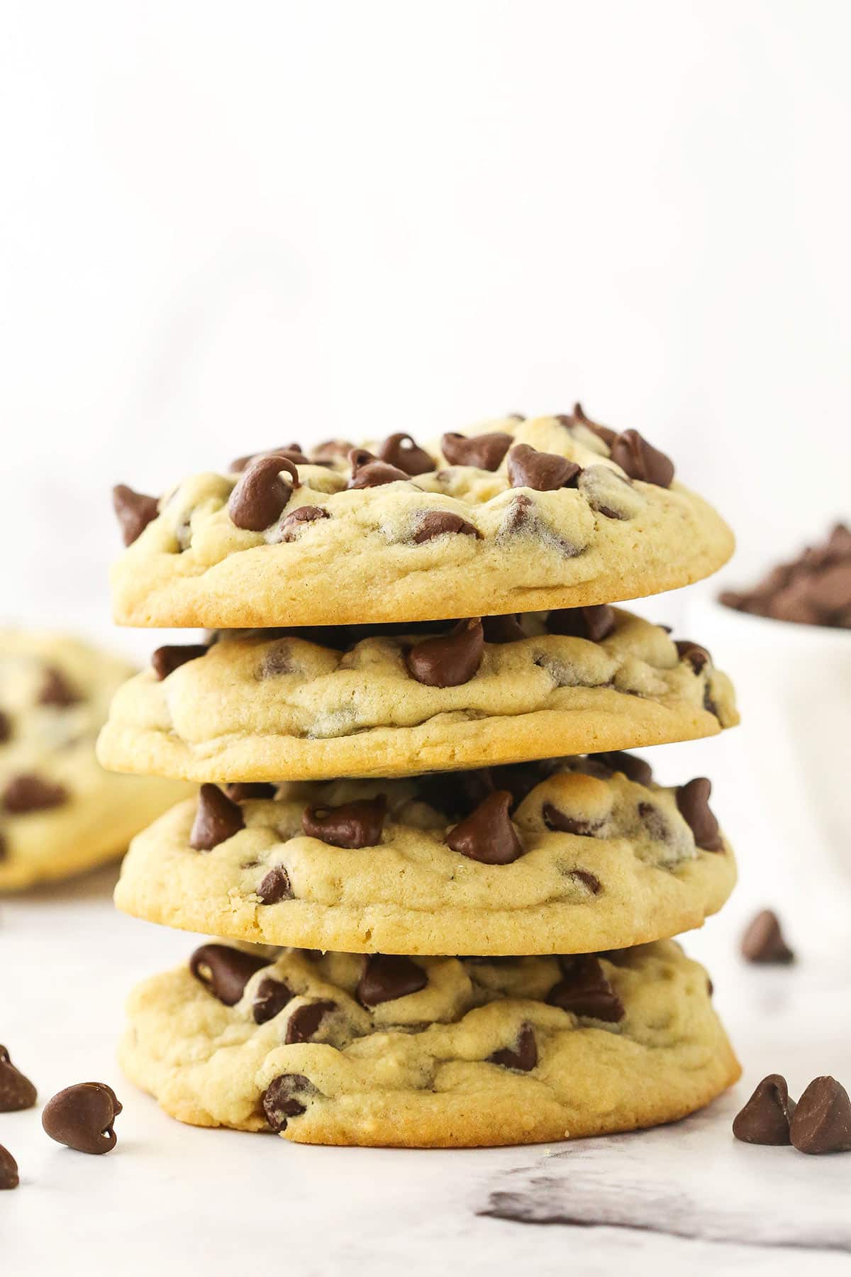 Four cooled chocolate chip cookies stacked on top of one another.
