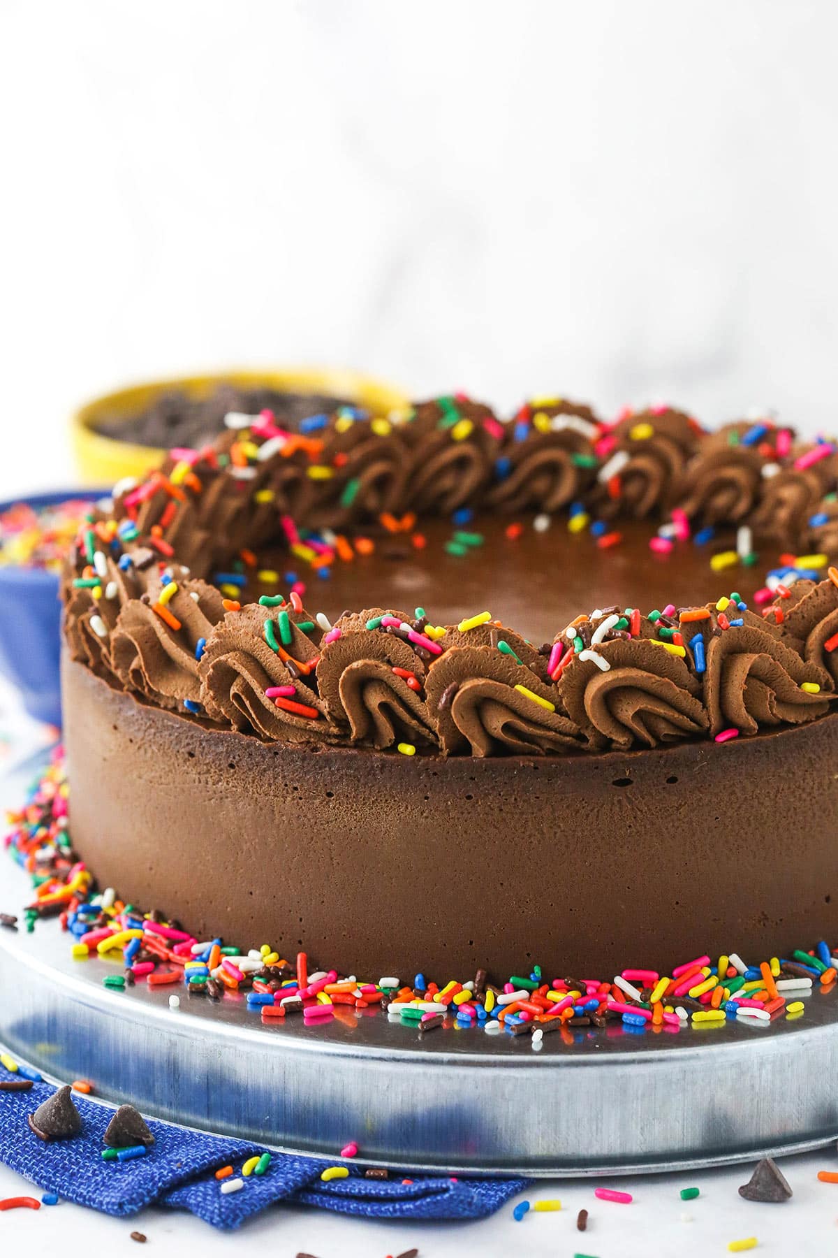 A homemade chocolate cheesecake on a kitchen countertop with a bowl of chocolate behind it