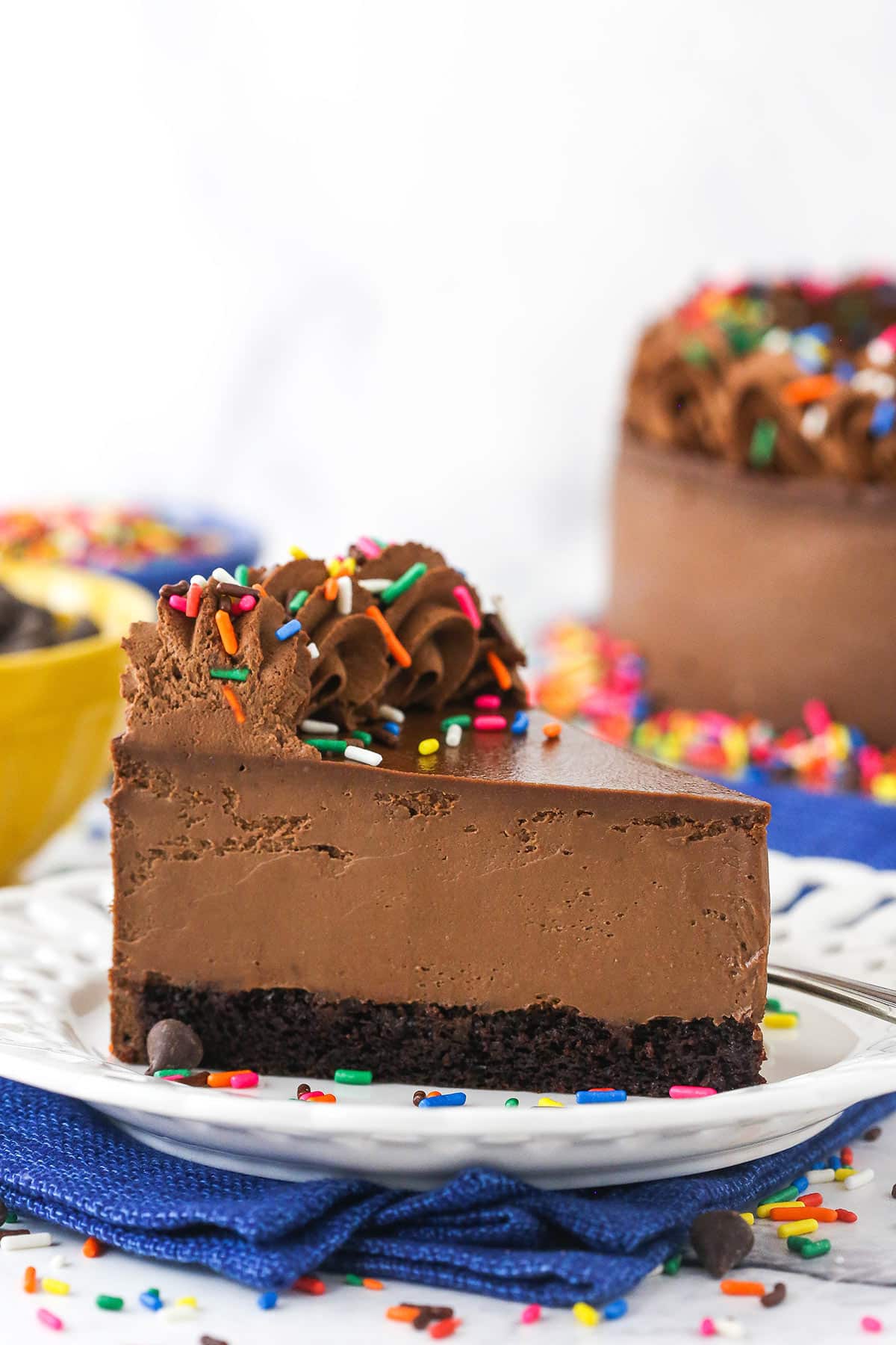 A piece of chocolate cheesecake on a dessert plate on top of a blue kitchen towel