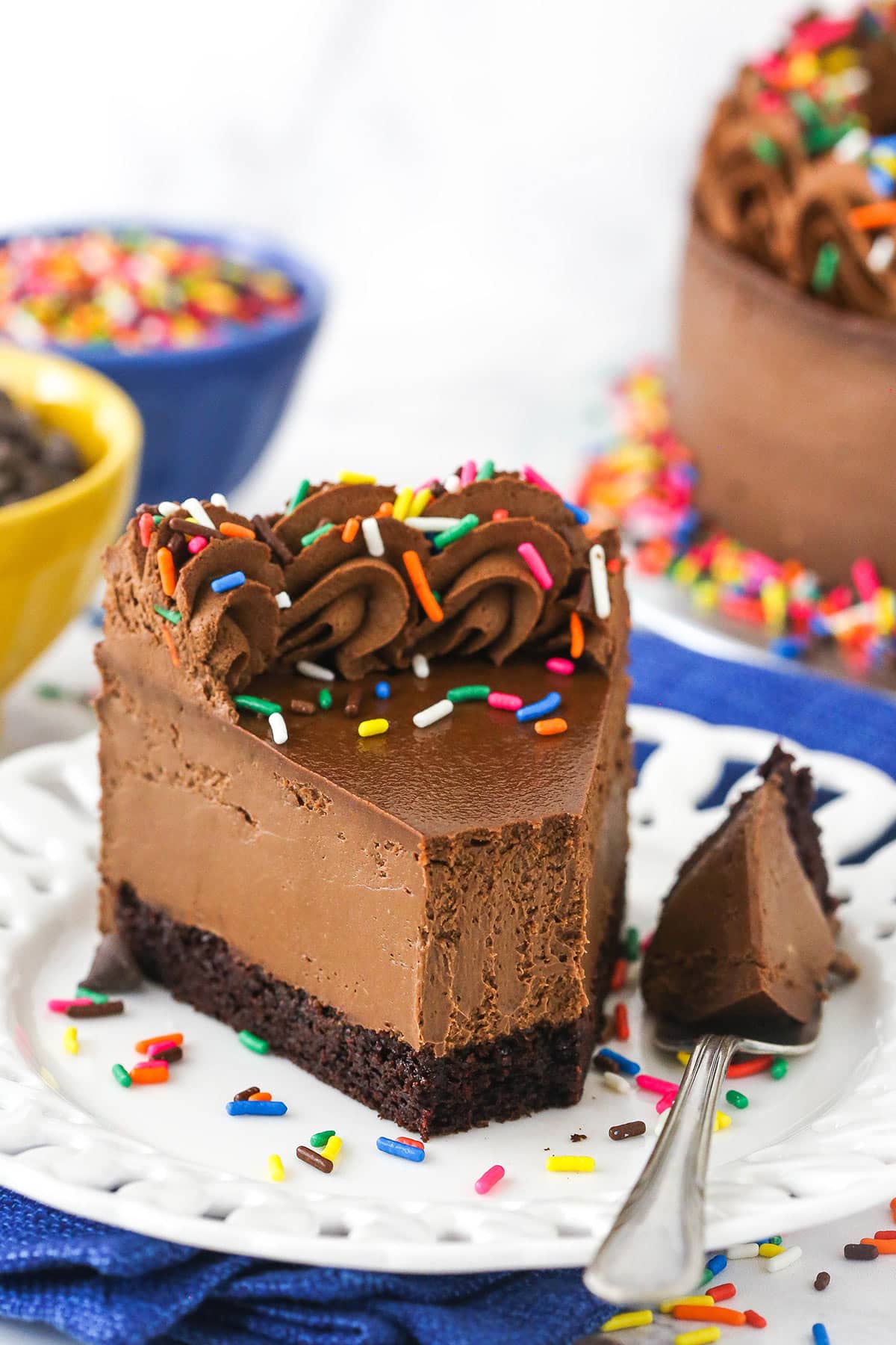 A slice of chocolate cake cheesecake on a plate with one bite on a fork