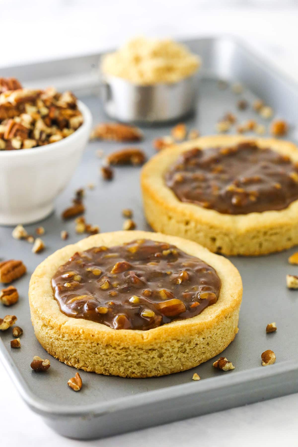 A copycat crumbl cookie on a baking sheet with a second cookie behind it