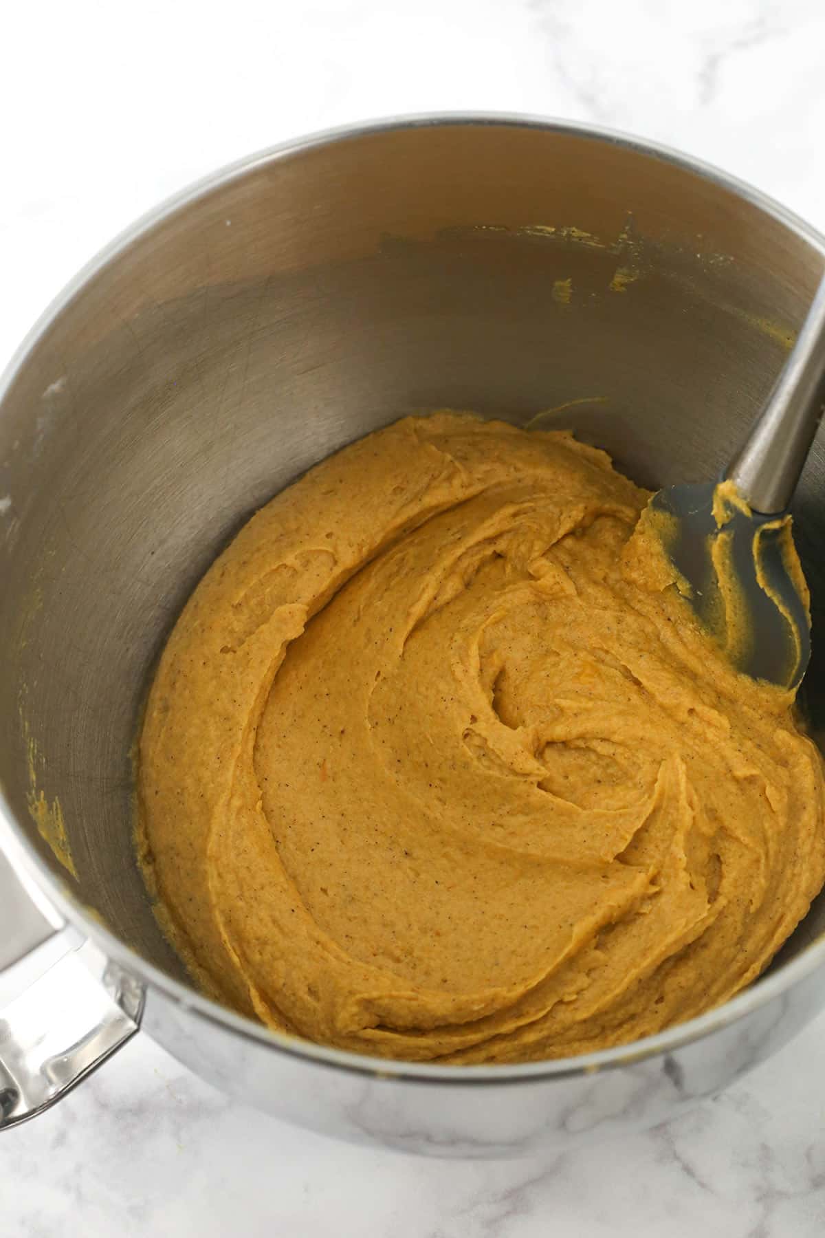 The finished pumpkin bread batter in a mixing bowl with a rubber spatula