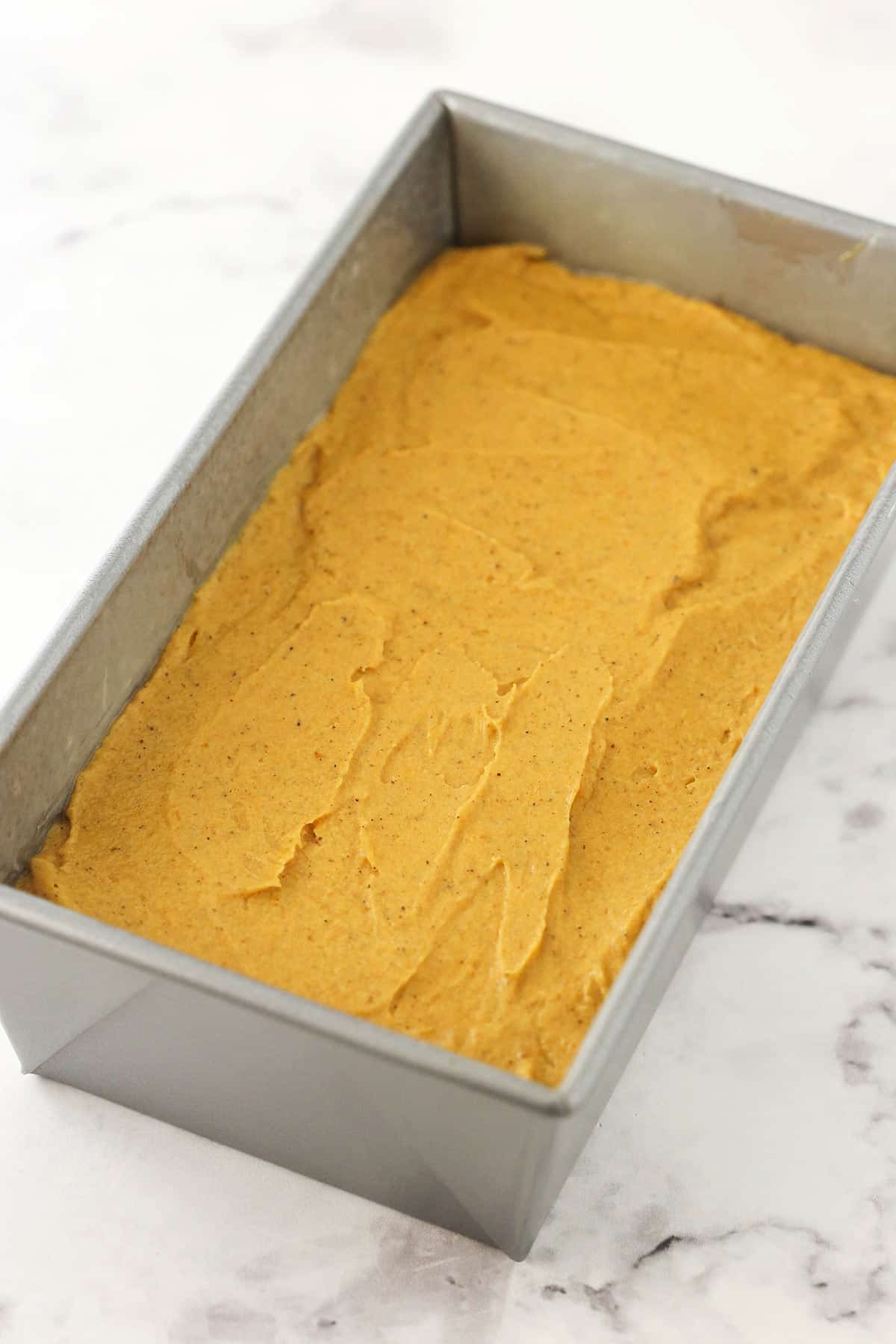 The loaf pan after the second layer of batter has been added on top of the filling