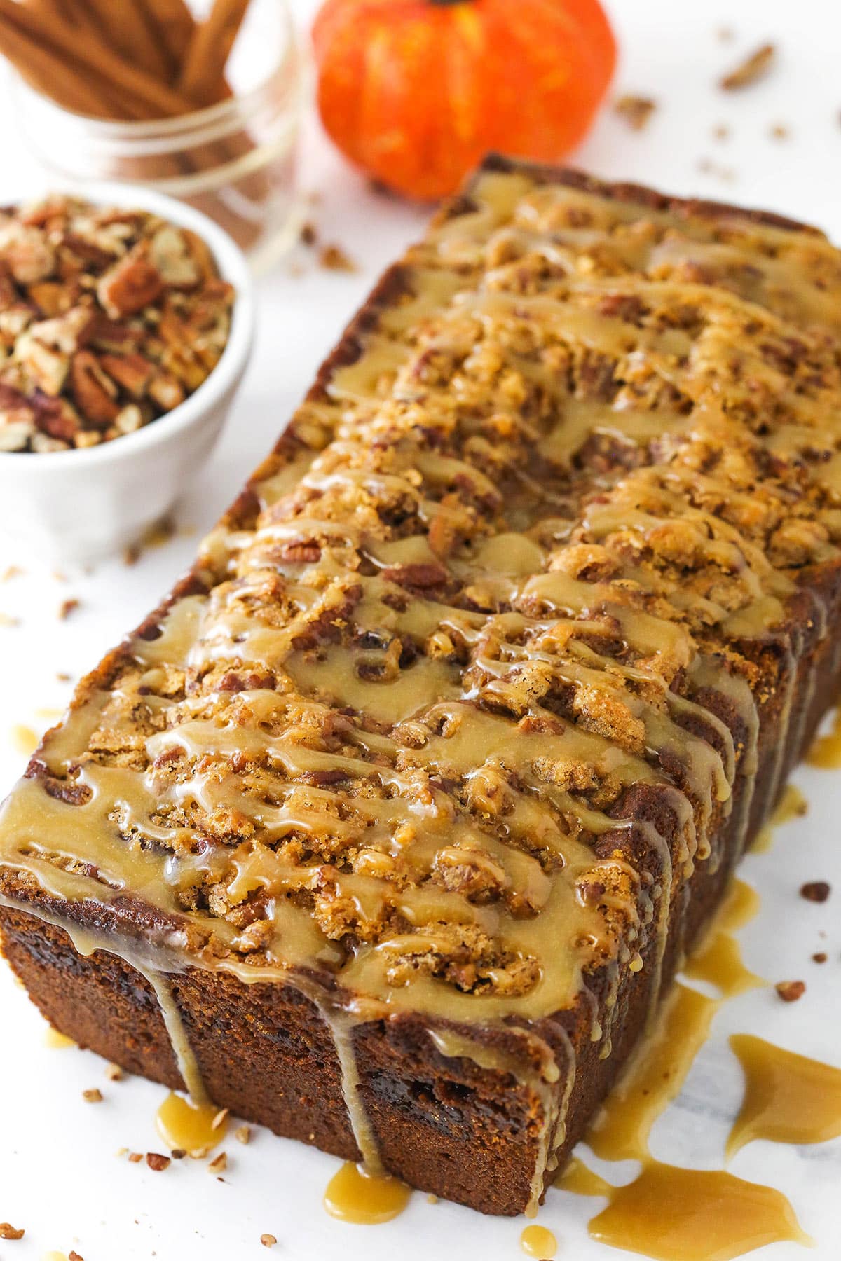 A loaf of homemade pumpkin bread covered in a drizzle of brown sugar icing