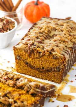 Half a loaf of praline pumpkin bread with a few individual slices in the foreground