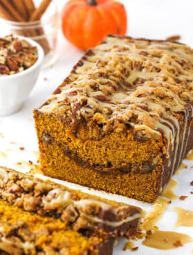 Half a loaf of praline pumpkin bread with a few individual slices in the foreground