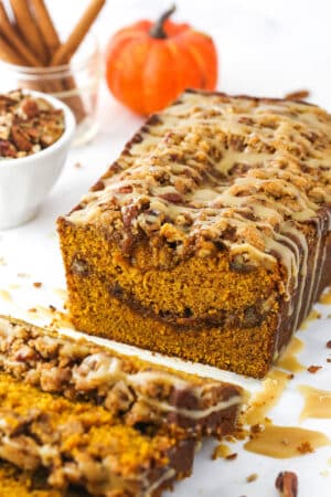 Half a loaf of praline pumpkin bread with a few individual slices in the foreground
