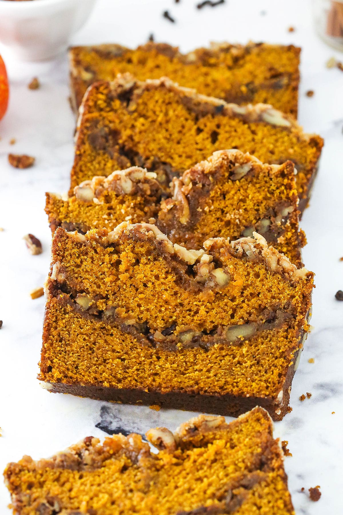 Slices of homemade pumpkin bread lined up on a kitchen countertop