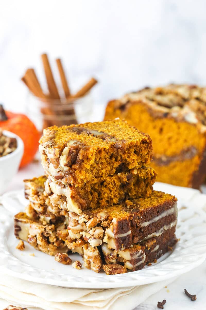 Two slices of praline pumpkin bread on a plate with a third slice broken in two equal halves