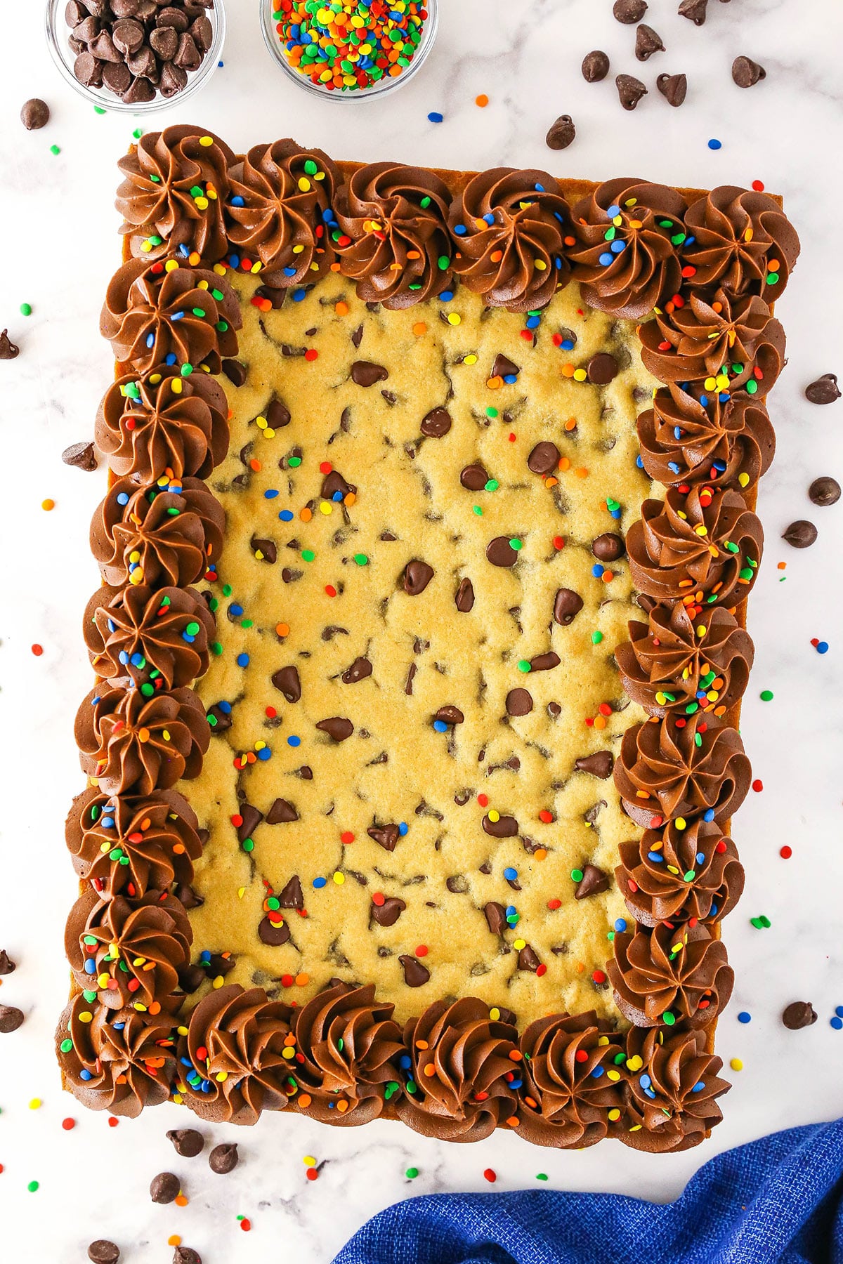 A sheet pan cookie cake on a marble surface with chocolate chips surrounding it