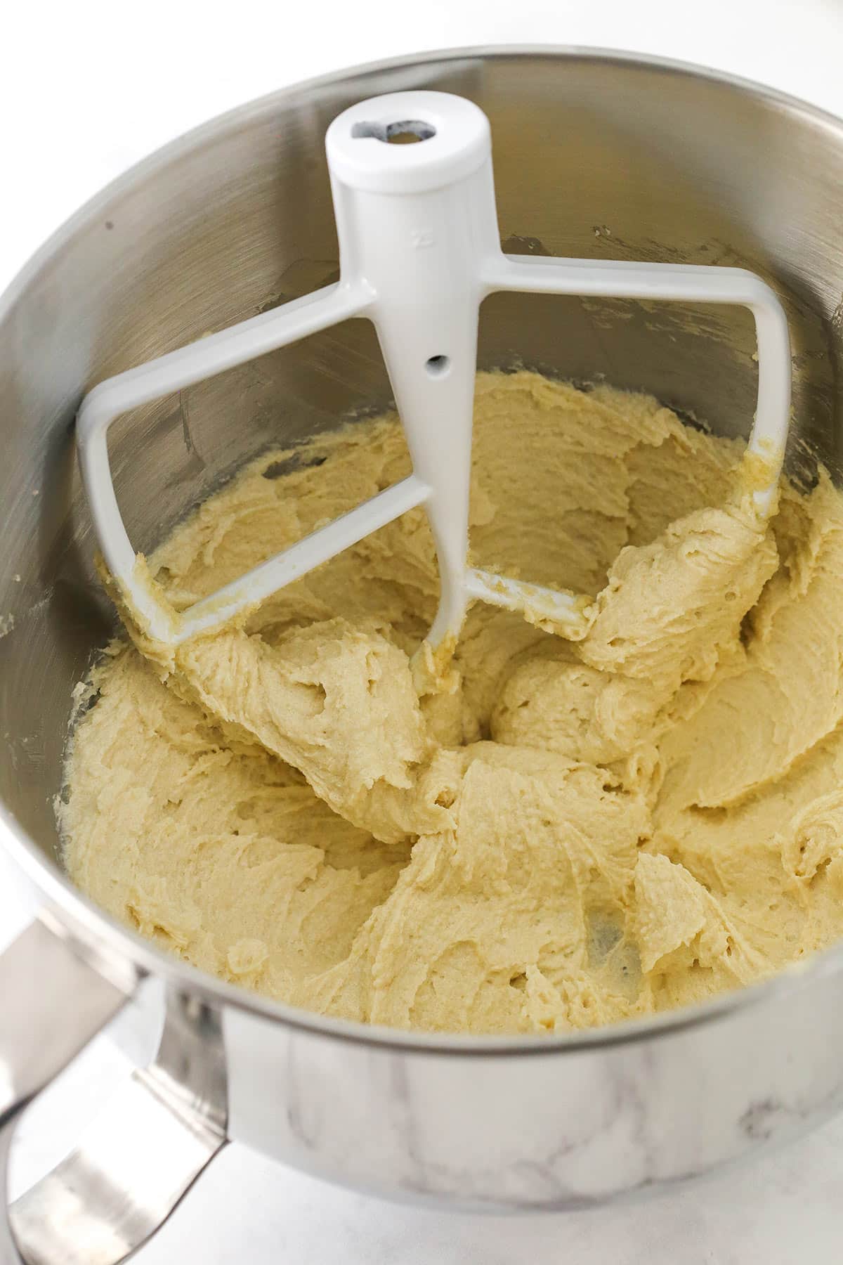 A creamy mixture of butter, sugar, egg and vanilla in an electric mixer bowl