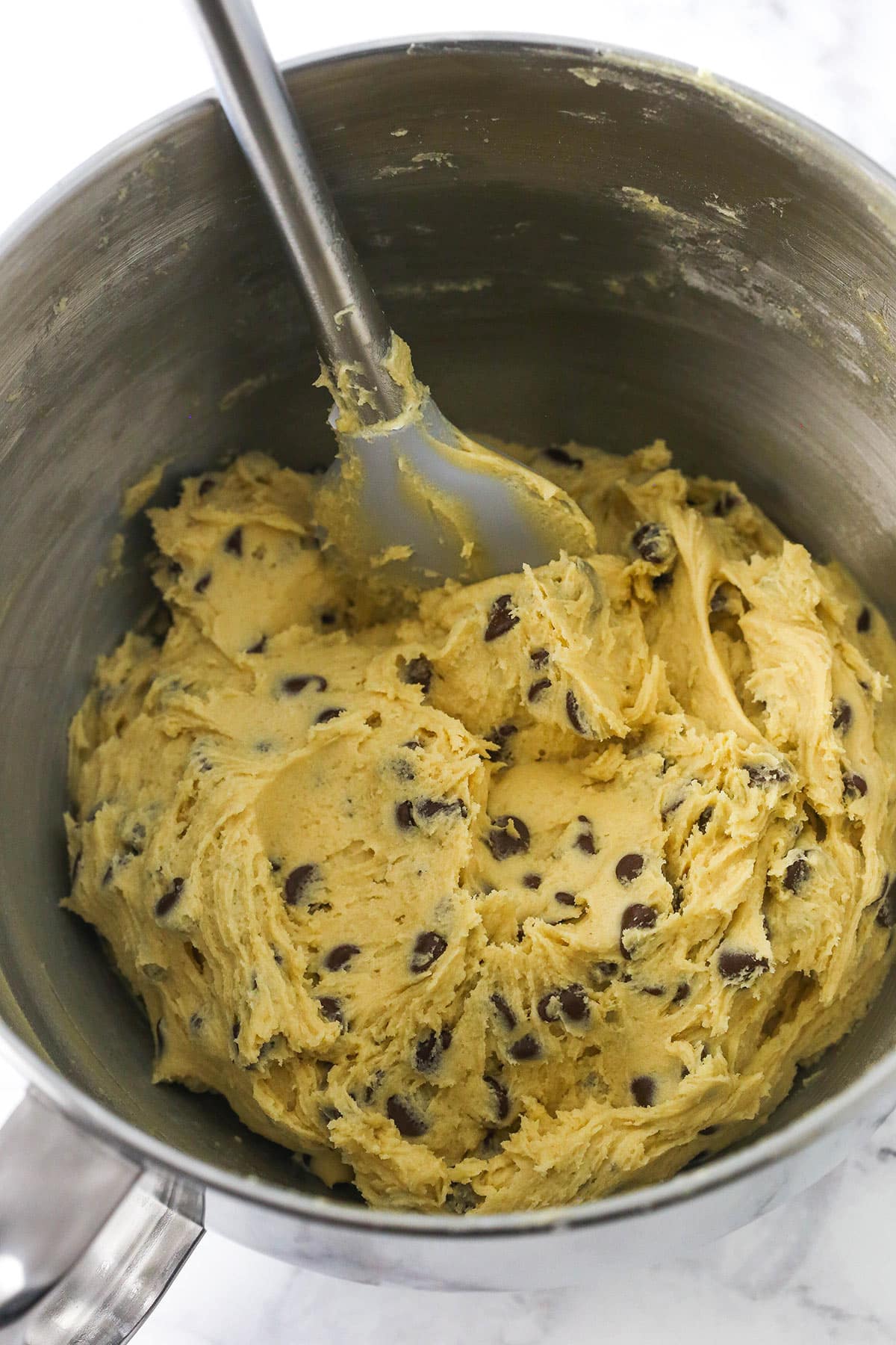 A bowl of homemade chocolate chip cookie dough with a spatula inside