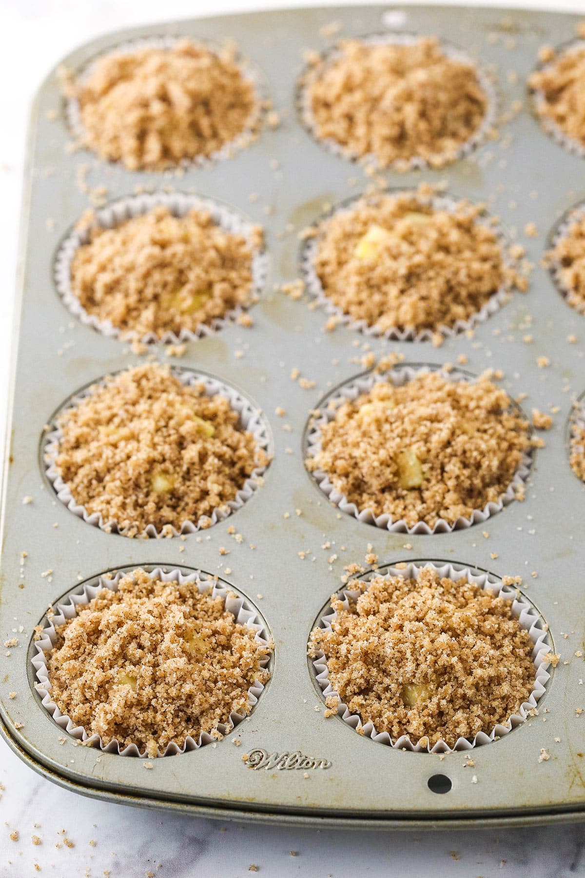 unbaked apple muffins and streusel in the muffin pan